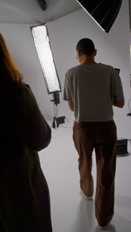 Vertical-Video-Of-Film-Director-Talking-With-Male-And-Female-Actors-Holding-Scripts-Rehearsing-For-Shooting-Movie-Or-Video-In-Studio-4